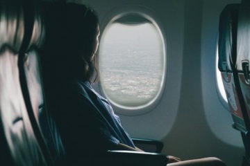 Une femme assise dans l'avion regarde par le hublot